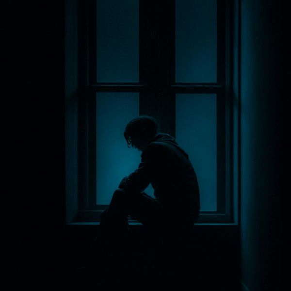 Person meditating peacefully in a minimalist setting with blue light.
